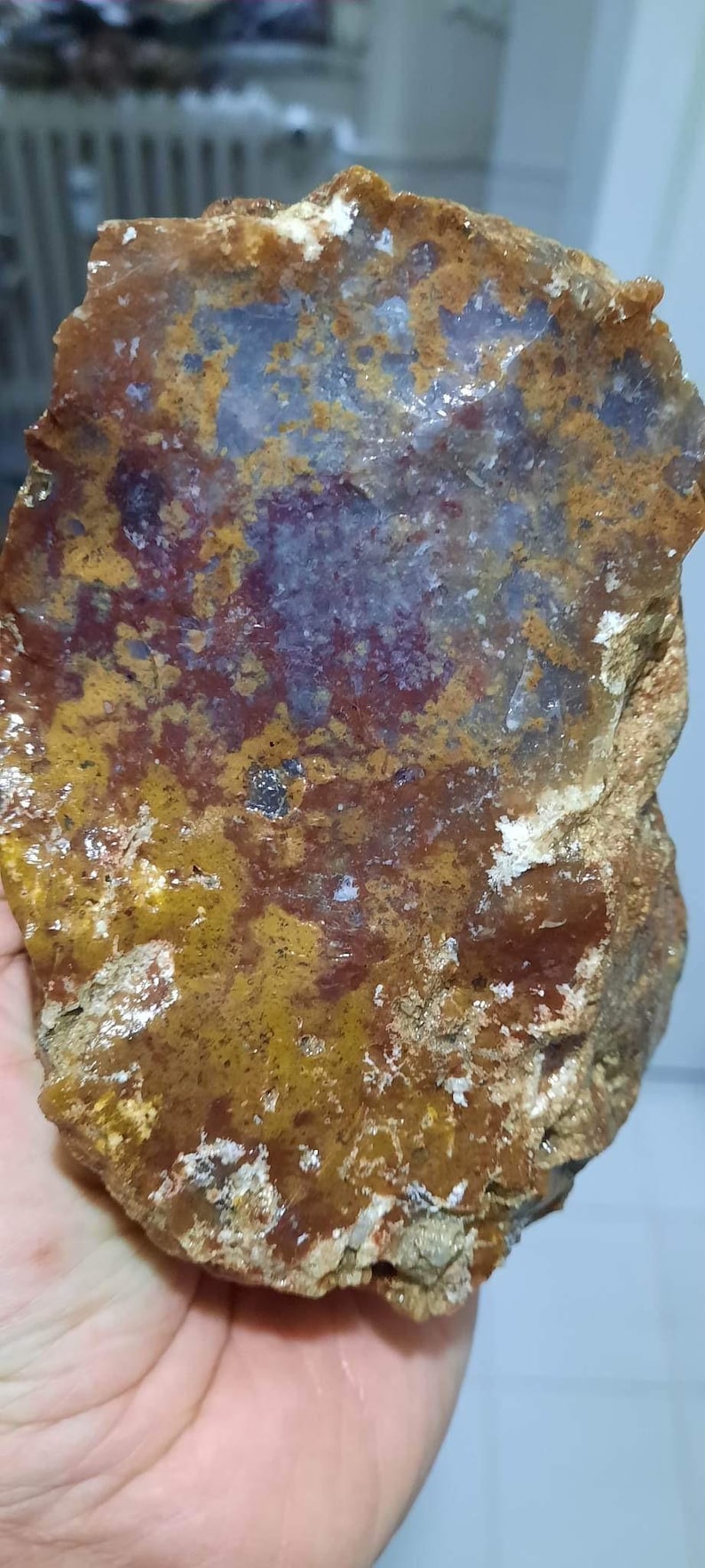 Pu&ograve; includere: Un grande pezzo di agata di forma irregolare con un motivo di colore marrone, arancione e viola. L'agata ha una superficie ruvida e testurizzata.