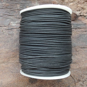 May include: A spool of black leather cord, wound tightly and ready for crafting projects.