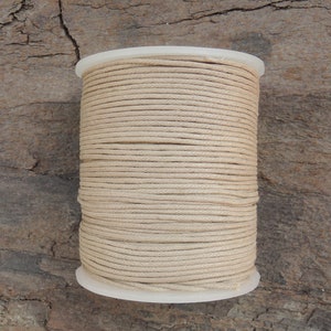 May include: A spool of natural beige cotton cord, wound tightly and ready for crafting projects.