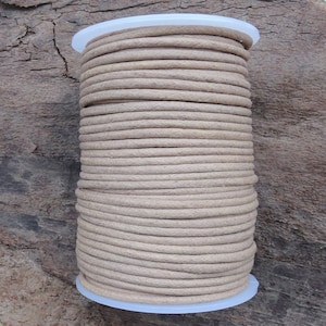 May include: A spool of beige leather cord, wound tightly and ready for crafting projects.