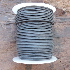 Può includere: Una bobina di cordoncino rotondo grigio scuro, avvolto strettamente su una bobina di plastica bianca. Il cordoncino sembra essere fatto di un materiale resistente, adatto a vari progetti di artigianato o gioielleria. Il cordoncino ha un diametro di circa 3 mm.