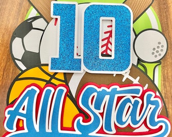 May include: Blue and white "10" with glitter, surrounded by sports balls, including a soccer ball, basketball, baseball, and golf ball. The text "All Star" is in blue with white and red outlines.