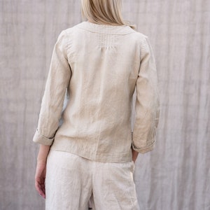 May include: A beige linen top and pants set with a long-sleeved button-up top featuring a V-neck and a gathered detail at the back.