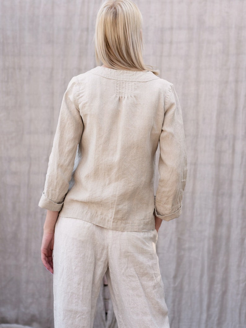 May include: A beige linen top and pants set with a long-sleeved button-up top featuring a V-neck and a gathered detail at the back.
