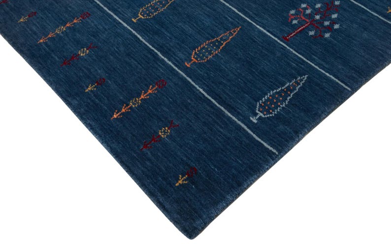 Angled close view of corner, thin low pile fold highlights soft wool weave on modern boho navy rug