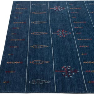 Close-up of linear striping and small geometric motifs, navy handwoven gabbeh carpet texture and edge detail