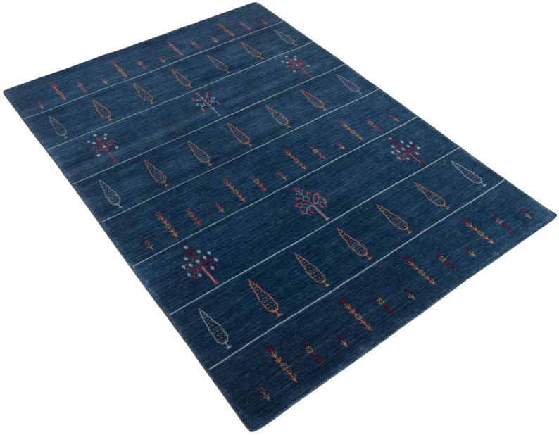 Angled perspective shows low pile texture on handwoven gabbeh carpet, deep navy stripes and motifs