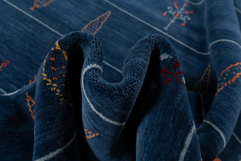 Draped close-up of wool fibers, rust and mustard accent stitches visible on navy pile, soft hand feel