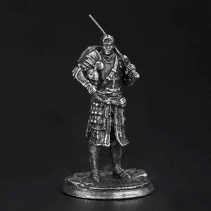 K&ouml;nnte beinhalten: Eine silberfarbene Miniaturfigur aus Metall, die einen Krieger auf einem runden Sockel darstellt. Die Figur tr&auml;gt eine detaillierte Plattenr&uuml;stung, h&auml;lt ein Schwert auf der Schulter und einen Helm unter dem Arm, mit feinen Texturen.
