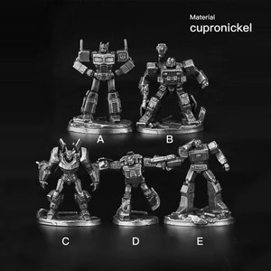 Könnte beinhalten: Fünf silberfarbene Roboterfiguren, die jeweils auf einem runden Sockel stehen. Die Roboter sind in verschiedenen Posen, einige halten Waffen. Die Sockel sind mit den Buchstaben A bis E beschriftet. Der Text "Material cupro nickel" befindet sich oben im Bild.