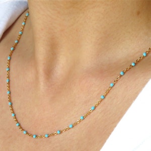 May include: A gold chain necklace with small turquoise beads.