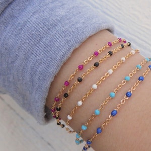 May include: Five gold chain bracelets with different colored beads. The bracelets feature turquoise, white, black, and pink beads.