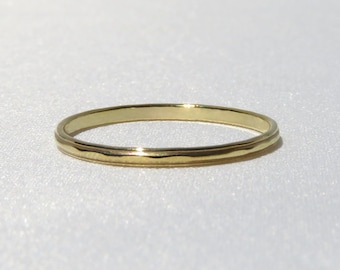 May include: A simple gold band ring with a slightly textured surface.