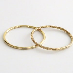 May include: Two gold rings, one with a smooth finish and the other with a textured finish.