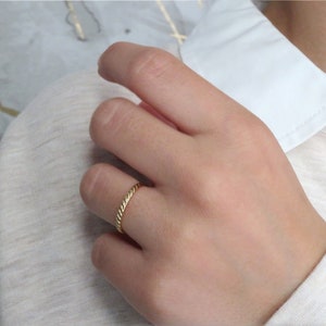 May include: A thin gold band ring with a twisted design.