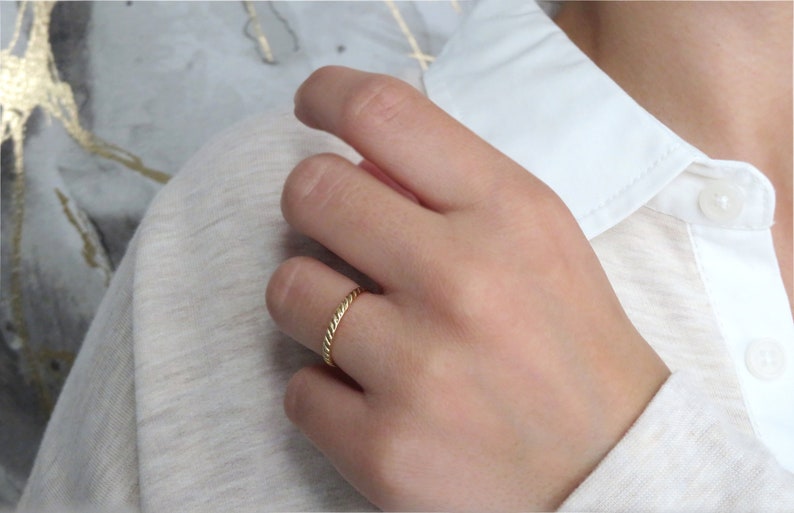 May include: A thin gold band ring with a twisted design.