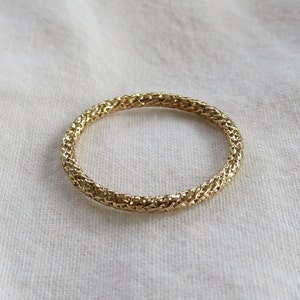 May include: A gold-toned ring with a textured, woven design.