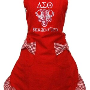 May include: Red and white gingham apron with a white embroidered elephant and the text "ΔΣΘ Delta Sigma Theta".