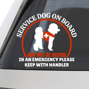May include: A white sticker on a car window with the text "SERVICE DOG ON BOARD" in a red circle. The sticker features a white dog wearing a red vest with a white cross. Additional text reads "MAY NOT BE VESTED, IN AN EMERGENCY PLEASE KEEP WITH HANDLER."