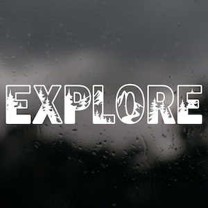 May include: A white vinyl decal featuring the word EXPLORE in bold capital letters. The interior of each letter contains a detailed silhouette graphic of a mountain range and evergreen pine trees, creating a nature-themed cutout design.