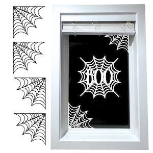 Peut inclure: Décorations d'angle et autocollants de fenêtre en toile d'araignée blanche pour Halloween. Le mot "BOO" est affiché dans un motif de toile d'araignée. La fenêtre est encadrée en blanc.