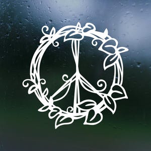 May include: A white peace sign surrounded by a wreath of leaves and flowers. The peace sign is a symbol of peace and love.
