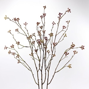 May include: Artificial floral stem featuring thin, brown branches adorned with small, round, reddish-brown buds. The buds have a speckled look, with some showing a touch of yellow-green. The stem is set against a plain white backdrop.