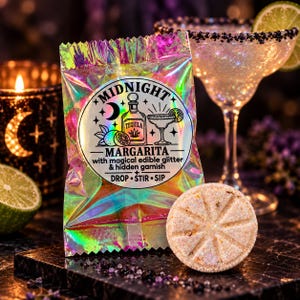 May include: A holographic pouch labeled Midnight Margarita with magical edible glitter & hidden garnish, featuring a tequila bottle and cocktail glass graphic. Beside it sits a round, textured, beige drink bomb with a star-shaped indentation.