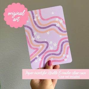 May include: A purple and pink paper insert with a wavy, abstract design and white stars. The insert is designed to fit inside a clear case for a Kindle e-reader. *Case not included*