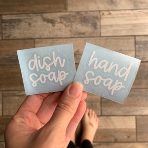 May include: Two blue square labels with white text. The label on the left says "dish soap" and the label on the right says "hand soap".
