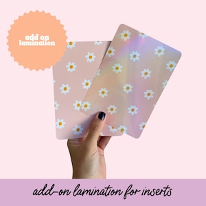 May include: Two pink cards with a white daisy pattern. One card has a holographic finish. The text "add on lamination" is on a peach starburst sticker. The text "add-on lamination for inserts" is at the bottom of the image.