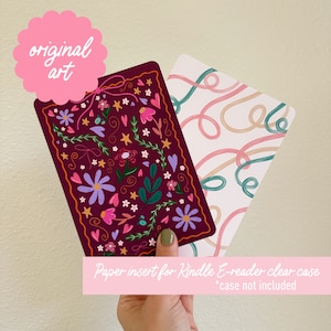 May include: A paper insert for a Kindle e-reader clear case, featuring a floral design with pink, purple, and green flowers on a burgundy background. The text "Paper insert for Kindle E-reader clear case *case not included" is printed at the bottom of the insert.