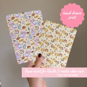 May include: Two paper inserts for a Kindle E-reader clear case, featuring a hand-drawn print. One insert has a pattern of baking tools and treats in pastel colors. The other has a butter stick pattern. The text "hand drawn print" is visible.