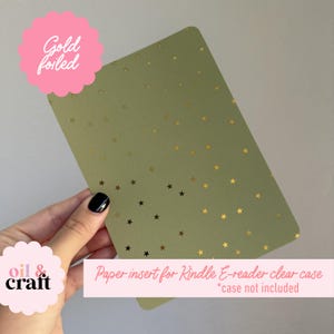 May include: A green paper insert for a Kindle E-reader clear case, adorned with gold foil stars. The text "Gold foiled" is in a pink circle, and the text "Paper insert for Kindle E-reader clear case *case not included" is in a pink rectangle.