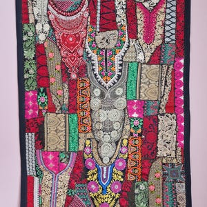 May include: A colorful patchwork wall hanging with intricate embroidery and embellishments. The fabric is a mix of red, green, gold, and pink, and the design features a variety of floral and geometric patterns.