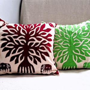 Puede incluir: Dos almohadas decorativas con fondo blanco y diseño de árbol. Una almohada tiene un árbol burdeos y la otra un árbol verde.