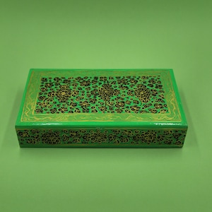 May include: A green rectangular box with a black and gold floral design. The box is made of papier-mâché and has a hinged lid.