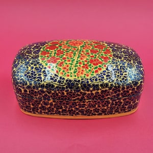 May include: A small, oval-shaped box with a blue and gold floral design. The box is made of paper mache and has a hinged lid.