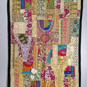 Pode incluir: Uma tapeçaria de parede de patchwork colorida com uma variedade de tecidos e bordados. A tapeçaria apresenta uma mistura de padrões florais, desenhos geométricos e motivos paisley em tons de verde, dourado, vermelho, azul e roxo.