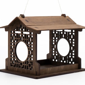 Op de afbeelding: Een houten vogelvoederhuisje met een decoratief traliewerk en een dak. De voederbak is ontworpen om aan een haak te hangen.