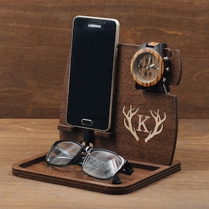Könnte beinhalten: Holztelefonständer mit Uhrenhalter, Brillenablage und einem personalisierten Initial "K" mit Geweih. Der Ständer ist aus dunkelbraunem Holz.