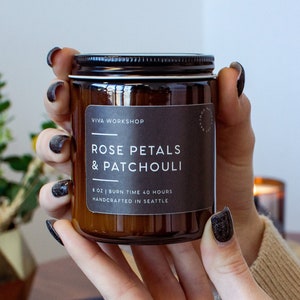 May include: A brown glass candle jar with a black label that reads "VIVA WORKSHOP ROSE PETALS & PATCHOULI 8 OZ | BURN TIME 40 HOURS HANDCRAFTED IN SEATTLE".