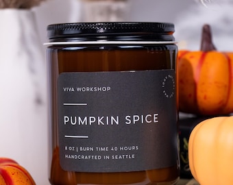 May include: A brown glass candle jar with a black label that reads "VIVA WORKSHOP" and "PUMPKIN SPICE". The label also states "8 oz | BURN TIME 40 HOURS | HANDCRAFTED IN SEATTLE". The candle is surrounded by small orange pumpkins.