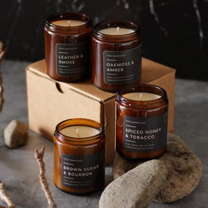 Puede incluir: Cuatro velas en frasco de vidrio &aacute;mbar con etiquetas negras. Las etiquetas dicen Leather & Smoke, Oakmoss & Amber, Spiced Honey & Tobacco y Brown Sugar & Bourbon. Cada vela de 8 oz tiene una mecha de algod&oacute;n centrada en cera blanca.