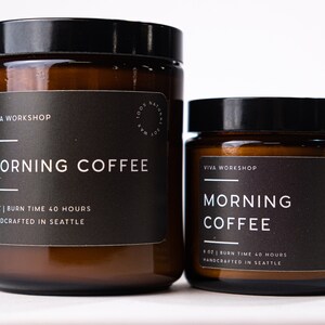 May include: Two brown glass candle jars with black labels. The larger jar is labeled "VIVA WORKSHOP MORNING COFFEE 8 OZ | BURN TIME 40 HOURS HANDCRAFTED IN SEATTLE". The smaller jar is labeled "VIVA WORKSHOP MORNING COFFEE 8 OZ | BURN TIME 40 HOURS HANDCRAFTED IN SEATTLE".