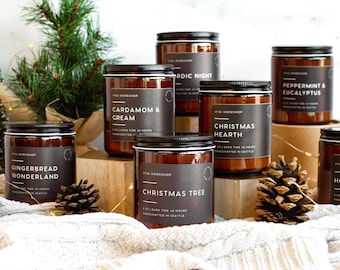 May include: A collection of amber glass jar candles with black labels featuring white text including Gingerbread Wonderland, Cardamom & Cream, Nordic Night, Christmas Hearth, Christmas Tree, and Peppermint & Eucalyptus, each marked 8 oz.