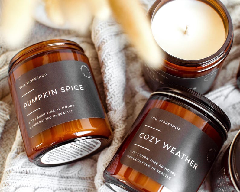 Puede incluir: Tres velas en frascos de vidrio &aacute;mbar con etiquetas negras. Una etiqueta dice PUMPKIN SPICE, 8 OZ, BURN TIME 40 HOURS, HANDCRAFTED IN SEATTLE. Otra dice COZY WEATHER, 8 OZ, BURN TIME 40 HOURS, HANDCRAFTED IN SEATTLE. Cera de color blanco.
