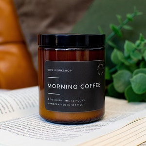 May include: A brown glass candle jar with a black lid and label. The label reads "VIVA WORKSHOP" and "MORNING COFFEE". The candle is 8 oz and has a burn time of 40 hours. It is handcrafted in Seattle.