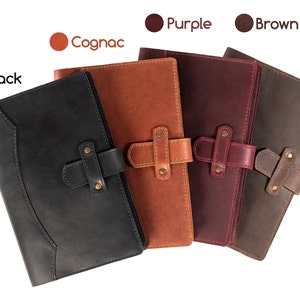Peut inclure: Plusieurs carnets en cuir noir, cognac, violet et marron. Chaque carnet est dot&eacute; d'une fermeture &agrave; rabat avec une sangle et des ferrures couleur laiton. L'image comprend des &eacute;tiquettes de couleur : Noir, Cognac, Violet et Marron.