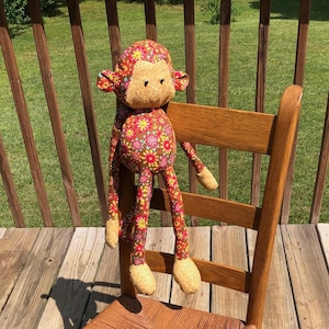 May include: A wooden rocking chair with a woven seat and a colorful monkey doll sitting on the back of the chair.